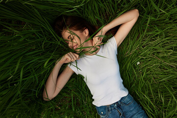 joyful, happy, carefree woman lies on the grass with her arms outstretched