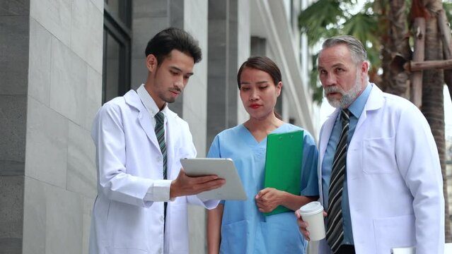 Professional medical staff people successful and teamwork concept. Diverse doctor and nurse walking and talking discussion on teblet together at hospital medical wellness center. Drink coffee