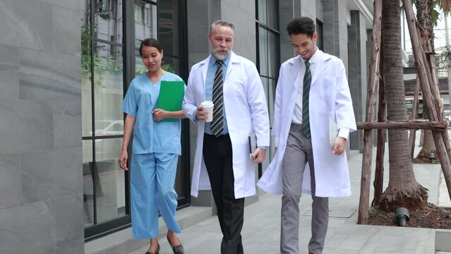 Professional medical staff people successful and teamwork concept. Diverse doctor and nurse walking and talking discussion on teblet together at hospital medical wellness center. Drink coffee