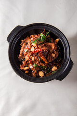 local cook live fresh catfish meat with spicy red dry chili asam sauce in big black claypot on wood table asian Chinese banquet halal seafood steamboat menu 