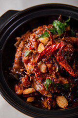 local cook live fresh catfish meat with spicy red dry chili asam sauce in big black claypot on wood table asian Chinese banquet halal seafood steamboat menu 