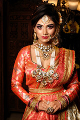 Magnificent young Indian bride in luxurious bridal costume with makeup and heavy jewellery with...