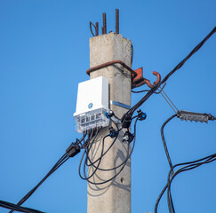 An electric meter on a pole against a blue sky