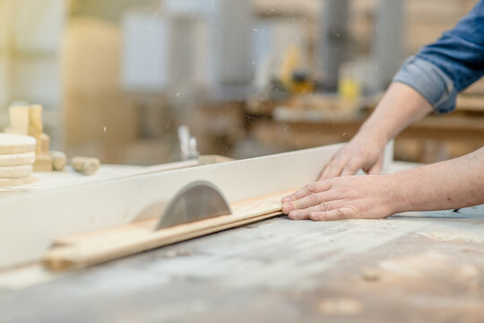 Carpenter cutting a piece of wood at workshop, using a circular saw