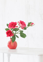  pink roses in pink vase on background old white wall