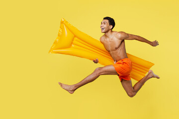 Full body sideways young sexy man wears orange shorts swimsuit relax near hotel pool jump high with...