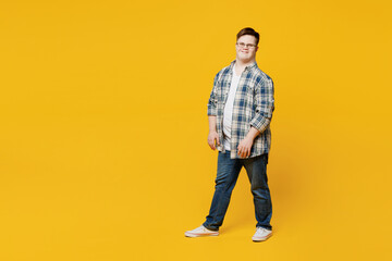 Full body young smiling cheerful fun man with down syndrome wears glasses casual clothes look camera walking going isolated on pastel plain yellow color background. Genetic disease world day concept.
