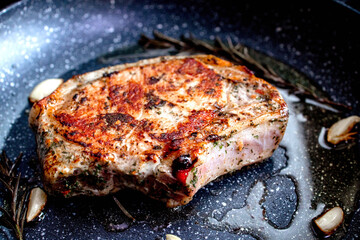 Grilled premium rib eye beef steak in the pan, cooking steak in the kitchen on a dark background. Overhead shot of chef preparing ribeye with butter, thyme and garlic.