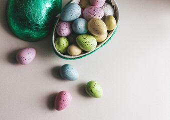 Ester egg filled with Easter sweets in green, blue, yellow and pink. With light background