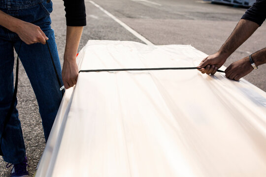 Man and woman securing wood paneling package with rope