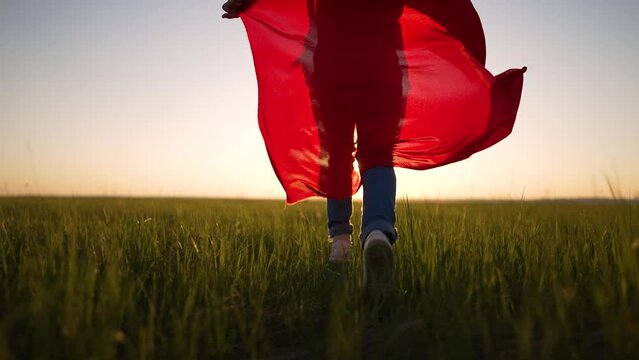 Happy girl run across the field at sunset. Smiling child in nature. Girl dressed as a superhero in park in nature. The child runs outdoors in the park. Girl winner run to victory. Happy family concept