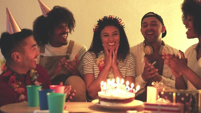 Woman blowing the candles of a birthday cake with friends