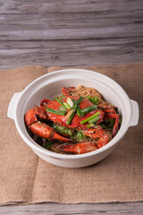 local wok fried Sri Lanka big fresh live crab with spicy onion garlic chilli salted egg yolk white pepper sauce vermicelli on wood table asian chinese halal food banquet seafood menu for restaurant