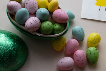 A heart full of Easter egg candies, colored feathers and an Easter card made by a child