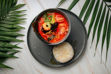 Portion of thai tom yam seafood soup with rice and nori
