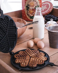 One freshly baked waffle, next to it are country eggs and a bottle of milk