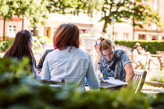Students meeting up for study session at sidewalk cafe outside library.