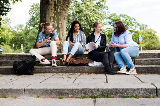 Students sitting on stairs outside library during study session.