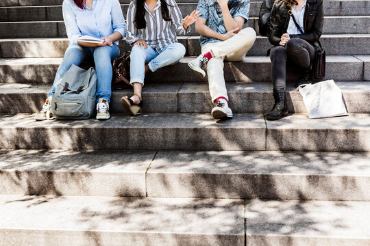 Students sitting on stairs outside library during study session.