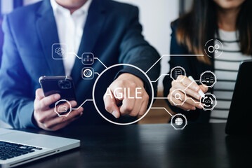 Agile development methodology concept. Business hand using laptop computer and tablet with virtual screen Agile icon on office digital technology concept..