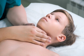 Fototapeta na wymiar Session of craniosacral therapy, cure of teen boy's jaw and neck by a doctor therapist. Craniosacral therapist touches the boy's cheeks and checks the correctness of the jaws at the hospital.