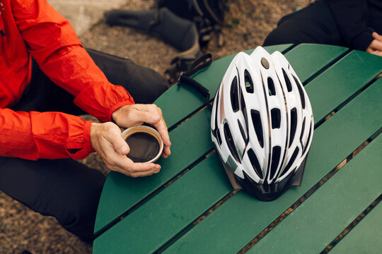 Man sitting with coffee at table with bike helmet on it