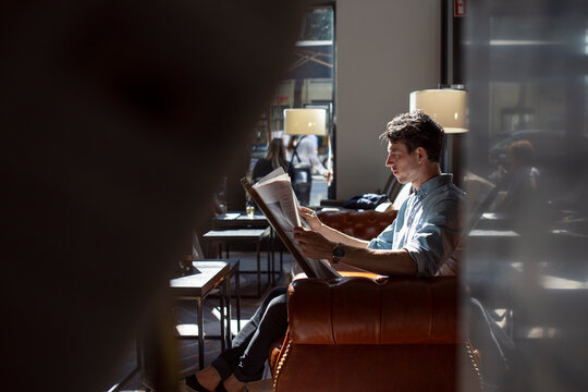Man reading newspaper in hotel lobby