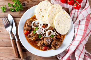 Beef goulash and dumplings (knedliky) on table from Czech Republic