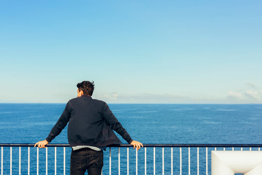 Man leaning on railing on ship deck