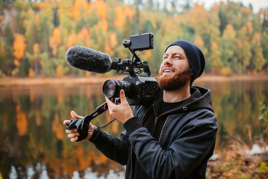 Man holding camera and filming nature in autumn landscape