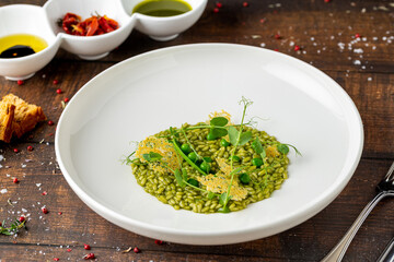 Pea risotto on a white porcelain plate in a fine dining restaurant