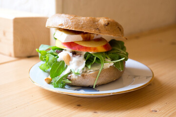 Delicious vegetarian sandwich on bagel bread. A bagel is a bread traditionally made from wheat flour and usually has a hole in the center.