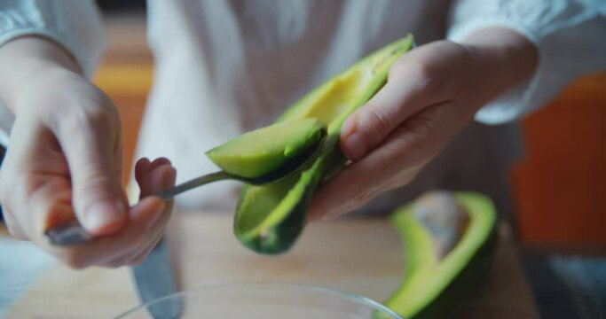 Swooping Avocado Flesh into Glass Bowl