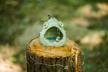 Decorative vases art objects in marine style on tree stump at outdoor art exhibition green forest...