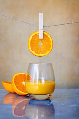 Orange juice glass with orange slice hanging by a clothes pin