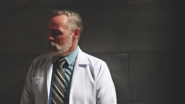 slow motion. Hight contrast and drama concept. Portrait caucasian senior man doctor posing and standing at wellness center and hospital. healthcare and medicine