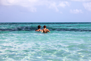 Couple swimming in azure sea water. Man with woman together, beach vacation