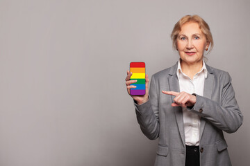 Happy senior mature woman showing modern smartphone with LGBT flag sceen. Stop discrimination,...