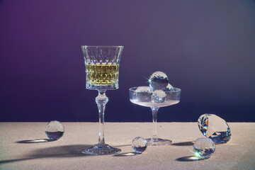 A glass of champagne wine or yellow beverage displayed with a glass containing diamond sphere on dark background