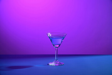 Martini cocktail glass filled with beverage isolated on gradient purple and blue. Alcohol drink, cocktail party concept. Night bar