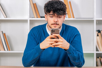 young male student looking at mobile phone smiling
