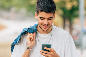 young male on the street walking looking at the mobile phone or smartphone