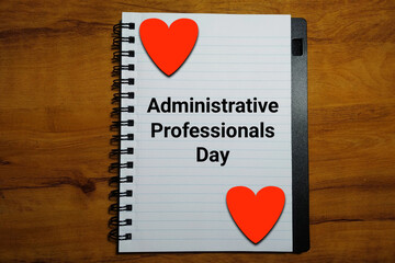 Administrative Professionals Day on notebook with heart on wood background