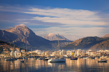 Calm morning walk along the seafront of port de Pollenca Majorca and the magnificent views of the bay and Tramuntana mountains backdrop - obrazy, fototapety, plakaty