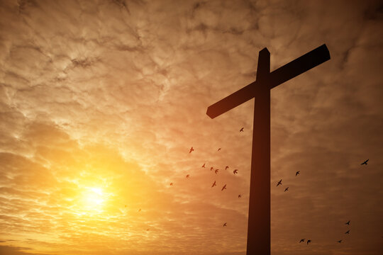 Christian cross with flying birds at sunrise. Resurrection of Jesus. Concept photo.