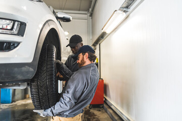 Fototapeta na wymiar professional mechanics changing a wheel on the car, car repair concept. High quality photo