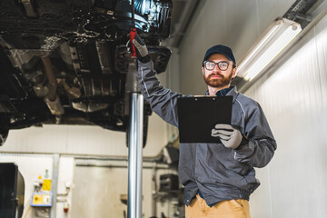 Caucasian professional mechanic making chassis inspection in the car workshop, medium shot. High quality photo