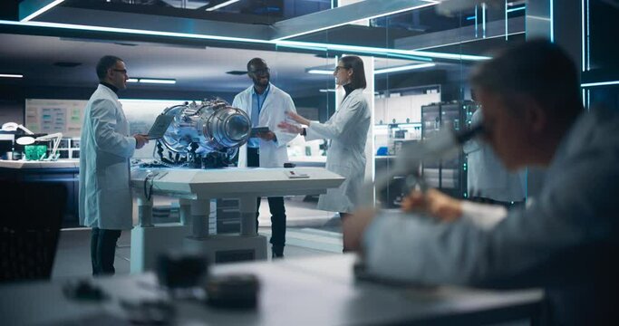 Rack Focus Switching from an Engineer Using Microscope to Propulsion Engineer, Scientist and Operators Working on an Innovative Turbine Motor, Standing with Computers in Scientific Technology Facility