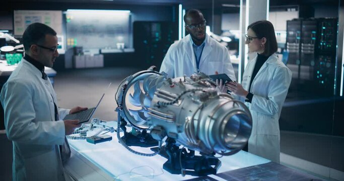 Airplane Engine Engineer and Scientist Work on a Futuristic Turbine Motor, Standing with Tablet Computer in Scientific Technology Lab. Professional Team Developing an Innovative Prototype Jet Engine