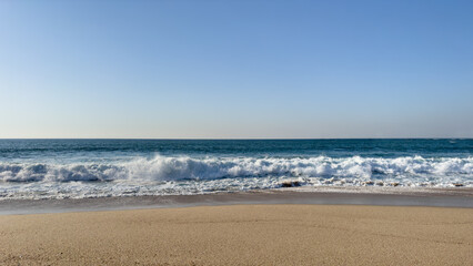 Fototapeta na wymiar Waves breaking on empty beach on a clear spring day in Povoa de Varzim, Portugal.